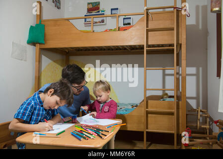 Fratelli colorazione con matite colorate mentre il padre è che li assistono, Monaco di Baviera, Germania Foto Stock