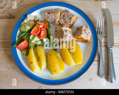 Pranzo snack di maiale imburrata torta di patate novelle bollite e insalata su una piastra di bianco con un bordo blu Foto Stock