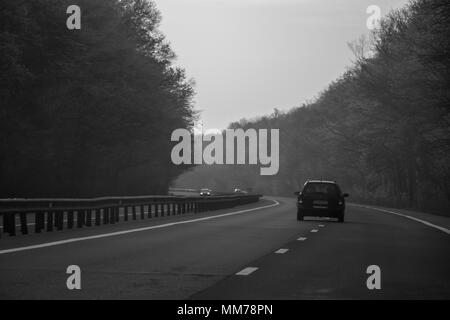 Un auto in autostrada in bianco e nero Foto Stock