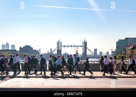 Mattina pendolari a Londra a piedi per lavorare attraverso il London Bridge con il Tower Bridge in background Foto Stock