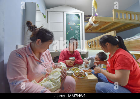 (180510) -- FUZHOU, 10 maggio 2018 (Xinhua) -- Tao Haiyan (L) con il suo secondo bambino in braccio ha il pasto con la sua famiglia nella sua nuova casa ridisegnato da Lan Feng al villaggio Xiyangxin Taijiang nel distretto della città di Fuzhou, capitale del sud-est della Cina di provincia del Fujian, 9 maggio 2018. Come un designer di interni della città di Fuzhou, Lan Feng ha prestato attenzione per le condizioni di vita dei lavoratori migranti in Fuzhou quando ha studiato all università. Più di un mese fa, Lan hai familiarità con Tao Haiyan da Chongqing, chi è in procinto di accogliere il suo secondo bambino, ma vive in una stretta e svantaggiati dimora Foto Stock