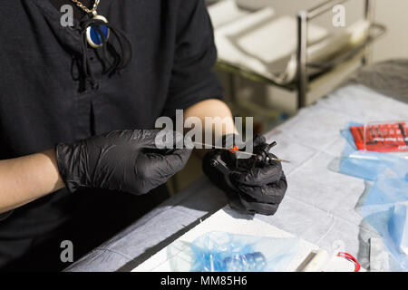 Master tattoo artist prepara gli strumenti per il tatuaggio. Foto Stock