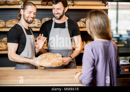 Donna comprare il pane nel panificio con uomo venditori Foto Stock