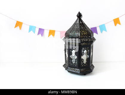 Ornamentali marocchino scuro, arabo lanterna sul tavolo bianco. Decorazione di partito, stringa di carta colorati bandiere. Biglietto di auguri per vacanza musulmana del Ramadan Kareem. Sfondo di festa. Foto Stock
