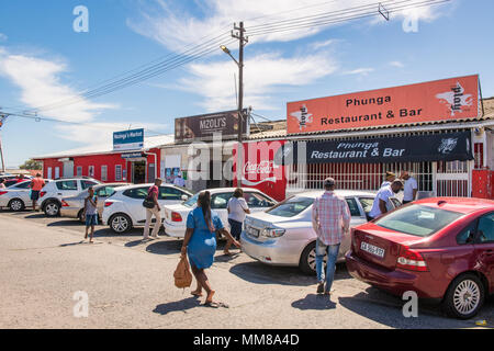 Un cluster di vetture si trova al di fuori di aziende locali come persone mill circa in Guguletu township di Città del Capo in Sud Africa Foto Stock