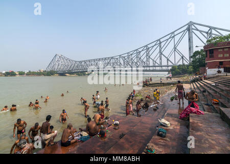 Kolkata, India - 12 Aprile 2017: Unidentified popolo indiano tenendo bagno nel fiume Hooghly con quella di Howrah bridge sullo sfondo a Calcutta, West Bengal, Foto Stock