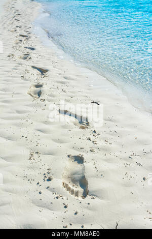 Orme nella sabbia con oceano blu a sinistra Foto Stock