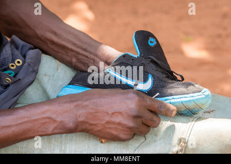 Uomo dello Zambia la pulizia di una delle sue scarpe da running Nike, villaggio Mukuni, Zambia Foto Stock