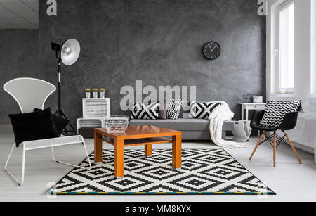 Grigio soggiorno con divano, sedie, lampada, piccolo tavolo in legno e decorazioni di pattern in bianco e nero Foto Stock