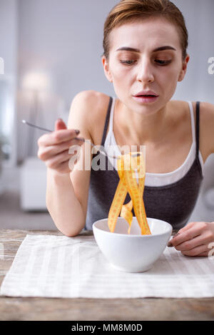 Triste cupa donna che guarda nel recipiente Foto Stock