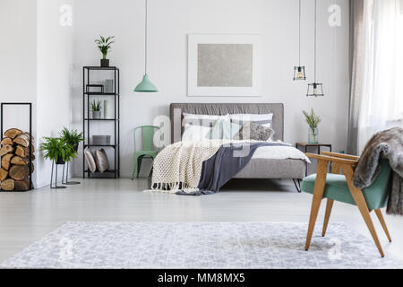 Letto king size con coperte e due sedie di menta in piedi in hotel stylish room Foto Stock