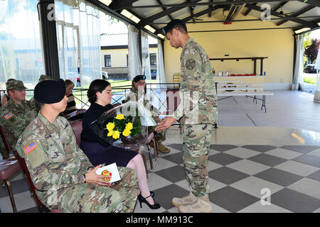 La moglie del comandante in arrivo, il cap. Eric P. Ng, riceve un bouquet di rose giallo da un soldato durante la modifica del comando cerimonia PER GLI STATI UNITI Army Garrison Italia Sede Società presso Caserma Ederle a Vicenza, Italia, Sett. 18, 2017. (U.S. Esercito foto di Visual Information Specialist Antonio Bedin/rilasciato) Foto Stock