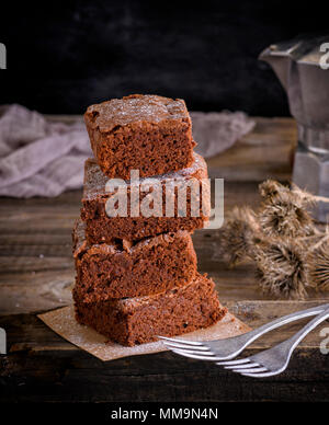 Pila di pezzi quadrati di brownie e due forcelle di ferro, close up Foto Stock