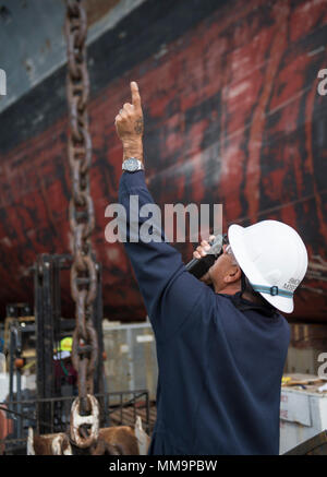 170921-N-LI768-1200 SAN DIEGO (sett. 21, 2017) Master Chief di Boatswain Mate Claus Moser comunica con i marinai nel castello di prua dell'assalto anfibio nave USS Makin Island (LHD 8) riducendo al contempo il carico di tribordo della catena di ancoraggio. Makin Island è attualmente in bacino di carenaggio di General Dynamics National la siderurgia e la costruzione navale Company (NASSCO) per un deposito di manutenzione di livello di disponibilità. (U.S. Foto di Marina di Massa lo specialista di comunicazione 2a classe Devin M. Langer) Foto Stock