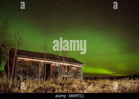 Northern Lights luce il cielo sopra una casa abbandonata in campagna Foto Stock