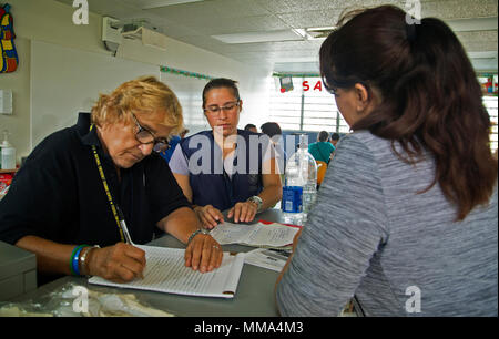 Vega Baja, PR, Settembre 27, 2017 - Kim Cosko, Disaster superstite specialista di assistenza (sinistra) e Regina Calderón, assistenza individuale specialista (centro), aiuto uragano María superstiti si applicano per la FEMA assistenza presso il rifugio situato nel Lino Padrón high school di Vega Baja. Yuisa Rios/FEMA Foto Stock