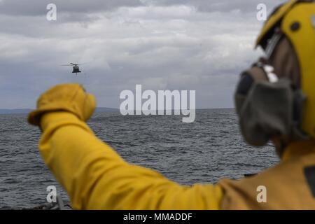 171003-N-FP878-058 mare irlandese (ott. 3, 2017) di Boatswain Mate 2a classe Shadi Azhari, da Dallas, segnali per un MH-60 Sea Hawk elicottero, attaccato al "Caricabatterie' di elicottero di mare squadrone di combattimento (HSC) 26, dal Arleigh Burke-class guidato-missile destroyer USS Donald Cook (DDG 75) durante l'esercizio comune della Warrior 17-2, Ottobre 3, 2017. Guerriero comune 17-2 è un REGNO UNITO-led, esercizio di multinazionali che sviluppa l'interoperabilità e la cooperazione in tutte le aree di guerra. (U.S. Foto di Marina di Massa lo specialista di comunicazione 1a classe Theron J. Godbold /rilasciato) Foto Stock