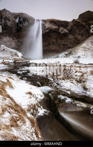 Spruzzi di acqua dalla cascata seljalandfoss su un paesaggio congelati nel sud dell'Islanda Foto Stock