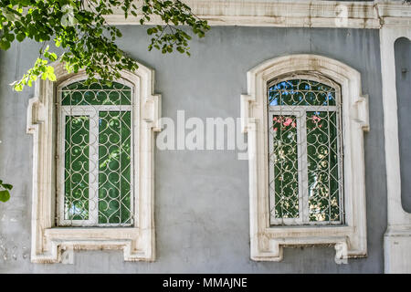 Parte della facciata del grigio di una vecchia casa in pietra con due finestre in bianco piattabande. Foto Stock