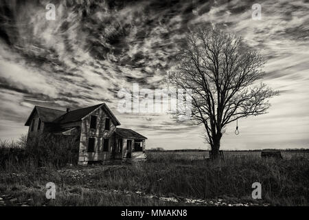 Foto in bianco e nero di un vecchio scary fattoria abbandonata che sta peggiorando con il tempo e l'incuria. Foto Stock