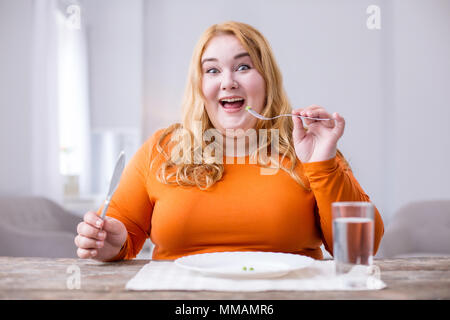 Alert donna grassa avente i piselli per la prima colazione Foto Stock