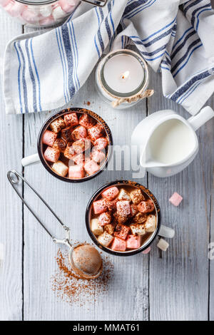 Cioccolata calda in due Bianco smaltato tazze con marshmallow sulla luce di un tavolo di legno. Vista dall'alto. Foto Stock