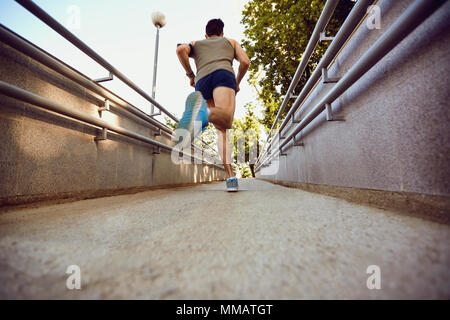 Un maschio di runner corre lungo la strada che porta al parco. Foto Stock