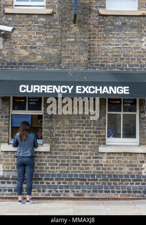 Una giovane donna presso il bancone di un ufficio cambio valuta o stand presso la Torre di Londra nella città di cambiare valuta in Sterline o Euro. Foto Stock
