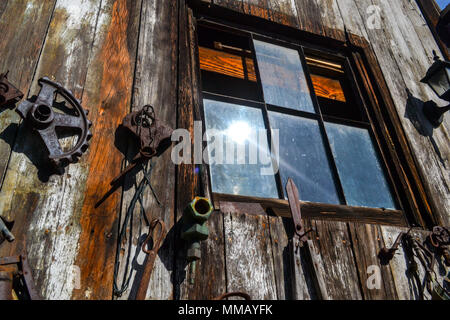 Rancho Bernardo in California - la più antica cantina di lavoro. Vintage scene arrugginita farm equipment per mulini a vento pigramente di filatura nella brezza. Fiori Foto Stock