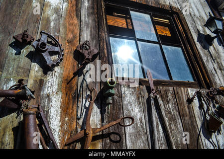 Rancho Bernardo in California - la più antica cantina di lavoro. Vintage scene arrugginita farm equipment per mulini a vento pigramente di filatura nella brezza. Fiori Foto Stock