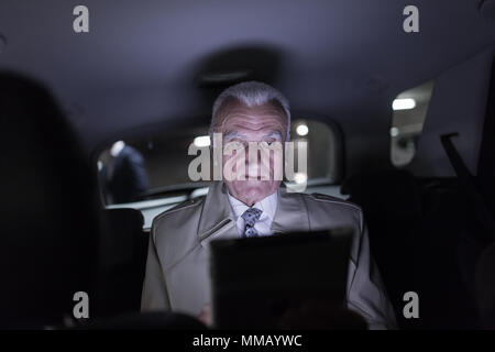 Imprenditore lavora in remoto in viaggio d'affari, con tavoletta digitale, seduto sul sedile posteriore di un taxi auto. Foto Stock