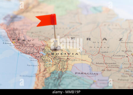 Piccola bandiera rossa segna il paese Sud Americano della Bolivia su una mappa del mondo. Foto Stock