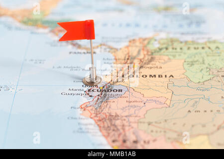 Piccola bandiera rossa segna il paese Sud Americano di Ecuador su una mappa del mondo. Foto Stock