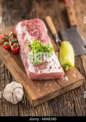 Lombo di maiale filetto alle erbe prezzemolo pomodori aglio peperoncino sale e spezie in cucina in legno bordo. Foto Stock