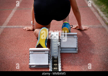 Atleta femminile sui blocchi di partenza su una pista di atletica Foto Stock