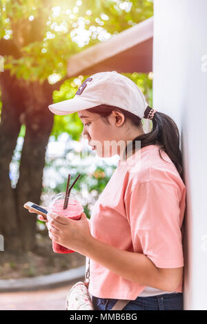 Cattiva abitudine di moderni giovani fat girl teen comportamento mangiare più di zucchero dessert e riproduzione di smartphone. Foto Stock