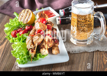 Grigliate gli spiedini di pollo con la tazza di birra Foto Stock