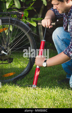 Primo piano immagine del giovane uomo utilizzando aria pompa per fissare flat pneumatico per bicicletta Foto Stock