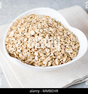 Il cibo. Laminato secco fiocchi di avena avena sulla ciotola. Mangiare sano concetto Foto Stock
