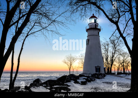 La storica Marblehead faro in Northwest Ohio sorge lungo le sponde rocciose del lago ghiacciato di Erie. Visto qui in inverno con un colorato sunrise Foto Stock