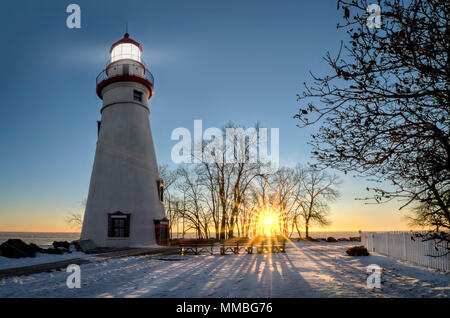 La storica Marblehead faro in Northwest Ohio sorge lungo le sponde rocciose del lago ghiacciato di Erie. Visto qui in inverno con un colorato sunrise Foto Stock