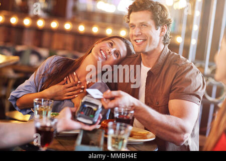 Carino coppia su una data presso il cafe pagando con carta di credito Foto Stock