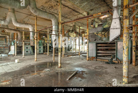 Distrutta la sala di produzione di un vecchio abbandonato fabbrica tessile con resti di attrezzatura guasta Foto Stock