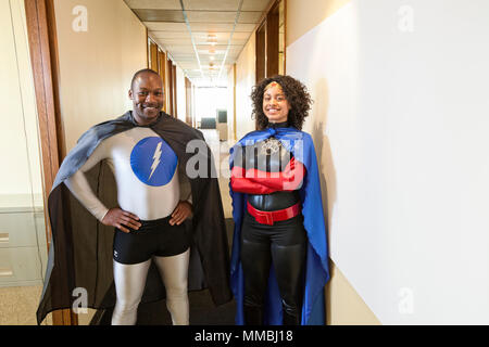 Un uomo e una donna team nero office super eroe in piedi in un corridoio del loro ufficio. Foto Stock