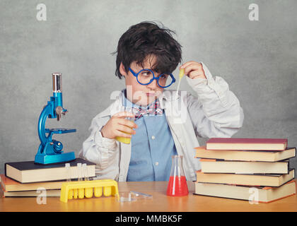 Ragazzo è di rendere la scienza esperimenti in laboratorio su sfondo grigio Foto Stock