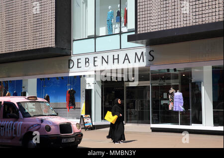 Signora araba in nero a piedi passato negozio Debenhams con Selfridges borsa di trasporto, su Oxford Street, nel West End di Londra, Inghilterra, Regno Unito Foto Stock