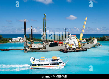 La barca passando dalla nave industriale con gru nella città di Nassau porta (Bahamas). Foto Stock