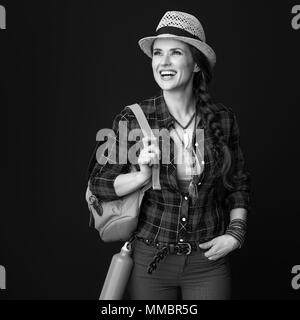 La ricerca di luoghi ispiratrice. Sorridendo viaggiatore attivo donna con zaino guardando in lontananza isolato su Foto Stock