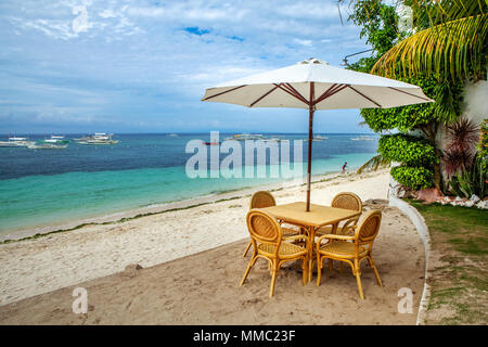 Un picnic sulla spiaggia tavolo con ombrellone istituito per i turisti di godere di una giornata presso la struttura Alona Beach, Panglao Island, Filippine. Foto Stock