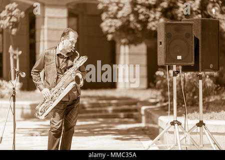 DIMITROVGRAD, Bulgaria - 30 Aprile 2018: musicista maschio gioca sul suo basso sassofono guardando lateralmente al concerto di strada evento dedicato alla giornat Foto Stock